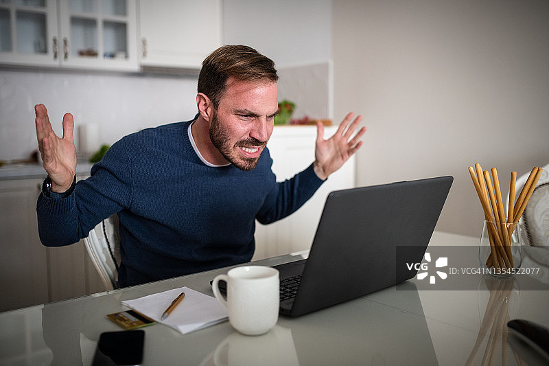 自由职业者坐在桌子前，面前放着一台笔记本电脑。他工作上遇到了问题，不知道该如何解决图片素材