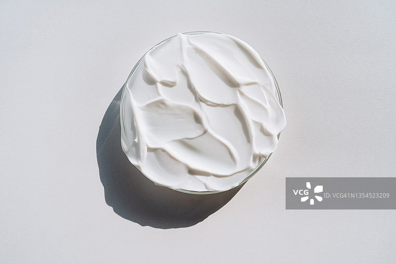 灰色背景下装满白色乳霜涂片的培养皿，化妆品实验室研究概念，平面拍摄图片素材