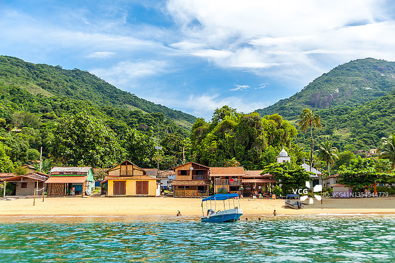 热带森林岛屿村庄和海滩前的船图片素材