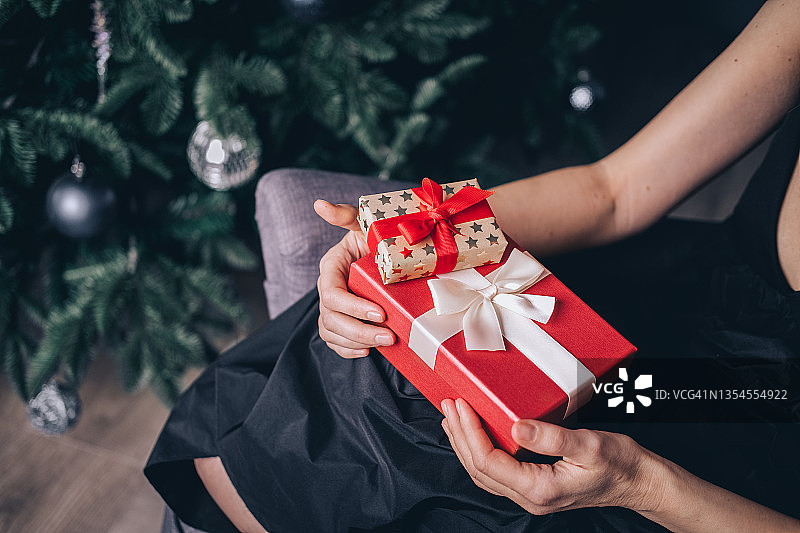 圣诞树前手捧礼盒的女人，新年庆祝概念图片素材