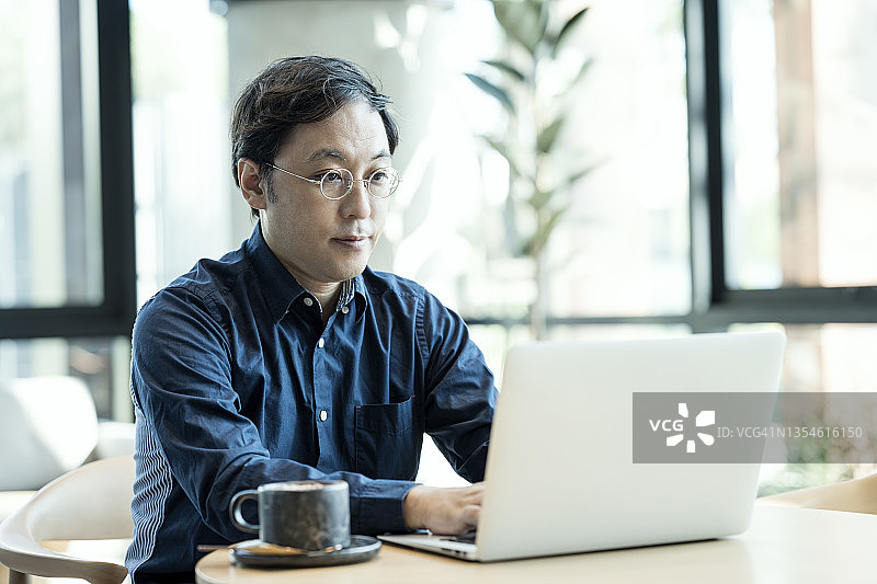 在现代酒店大堂工作的日本中年商人，提供远程办公协作方案图片素材