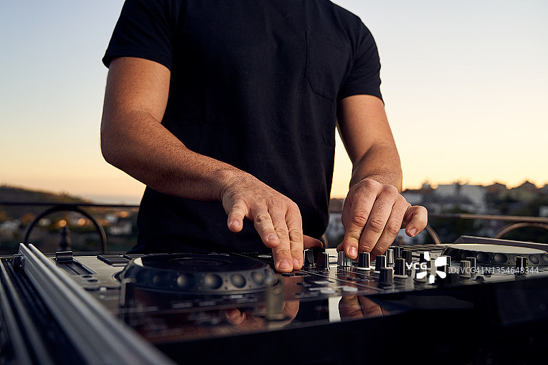 一位男DJ在露台的日落派对上用调音台播放音乐图片素材