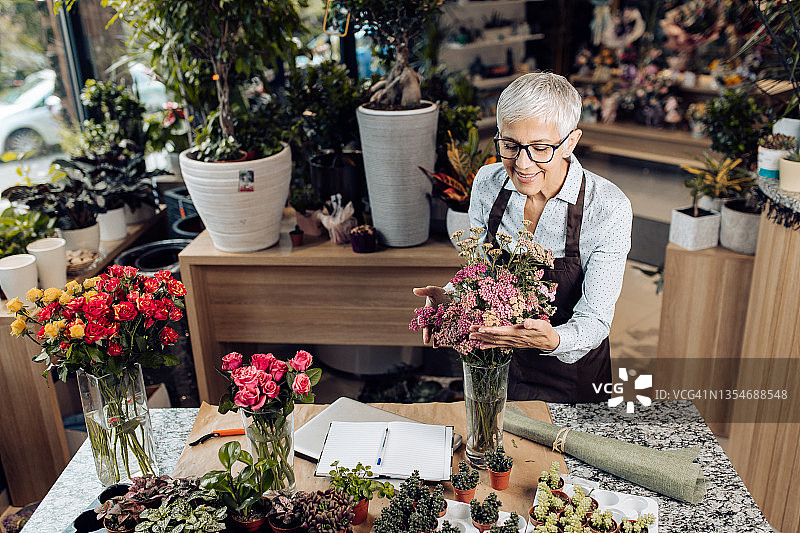 享受插花乐趣的快乐中年花艺师肖像图片素材
