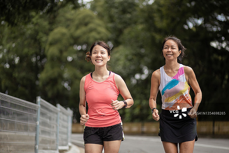 侧面：两名中国女运动员在田径跑道上跑步图片素材