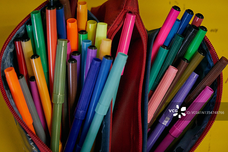 高角度特写：黄色背景上笔盒里的彩色笔图片素材
