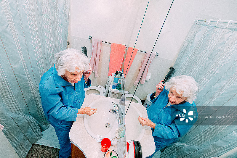 百岁老妇人照镜梳头的高角度镜头图片素材