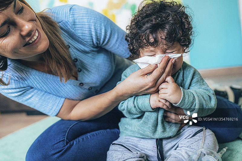 母亲帮助小儿子擤鼻涕图片素材