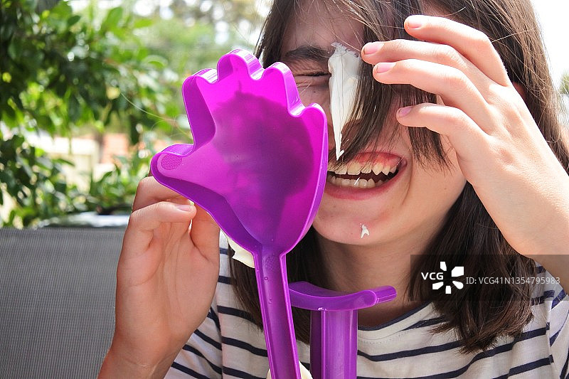 脸上沾满甜奶油的年轻女孩图片素材