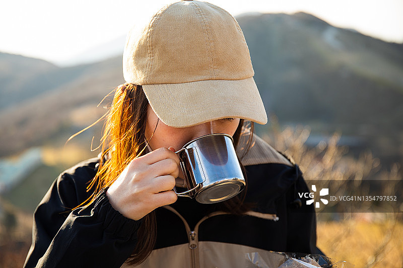 一名女性徒步旅行者在山中享受饮料图片素材