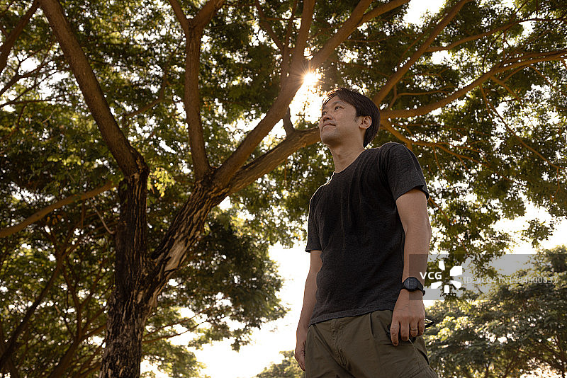 在户外公园，绿色背景下的亚洲男人图片素材