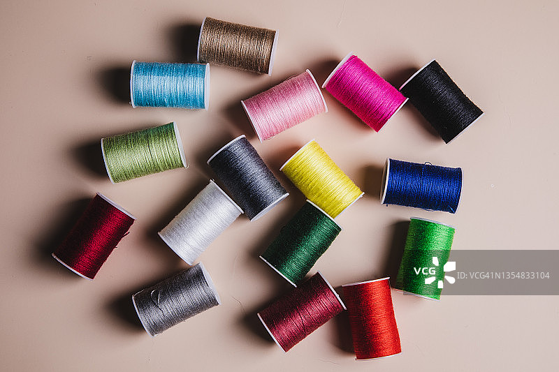 米色背景下的彩色缝纫线图片素材