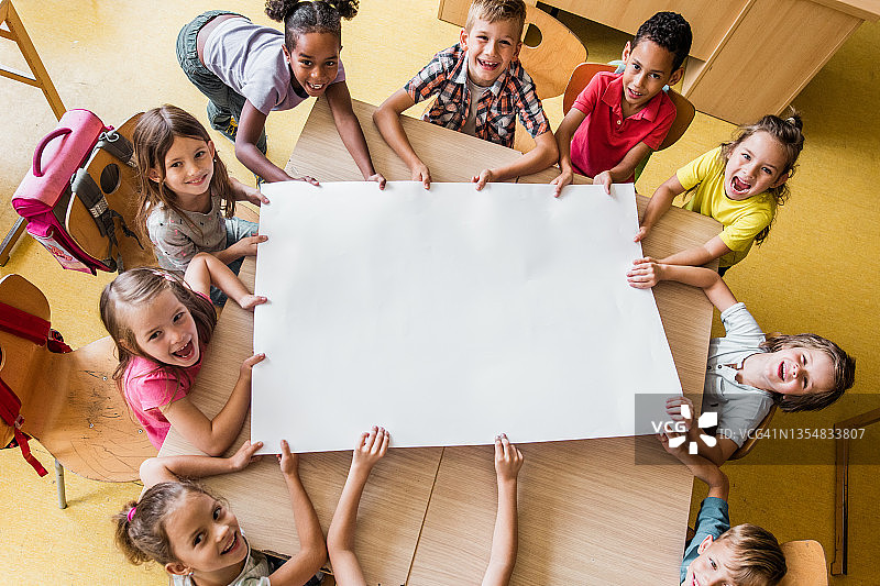 快乐的小学生在教室里拿着空白纸的俯视图图片素材