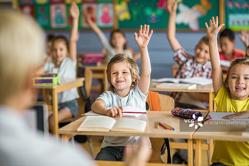 一群快乐的小学生在课堂上举手回答问题图片素材