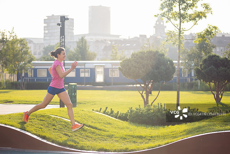 在城市专用跑道上慢跑的短裤年轻女人图片素材