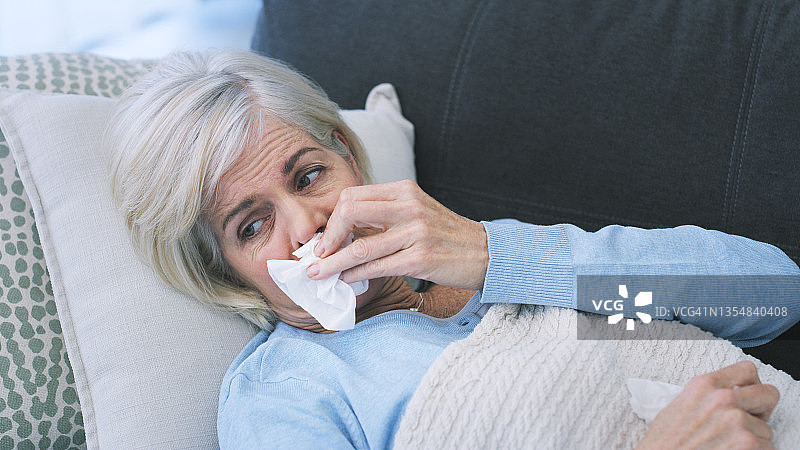 生病的老年妇女在家里的沙发上休息图片素材