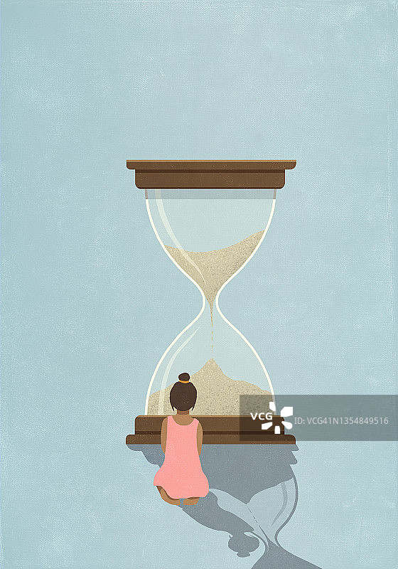 女孩看着沙漏里流逝的沙子图片素材