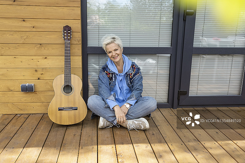 坐在露台上弹吉他的快乐女人肖像图片素材