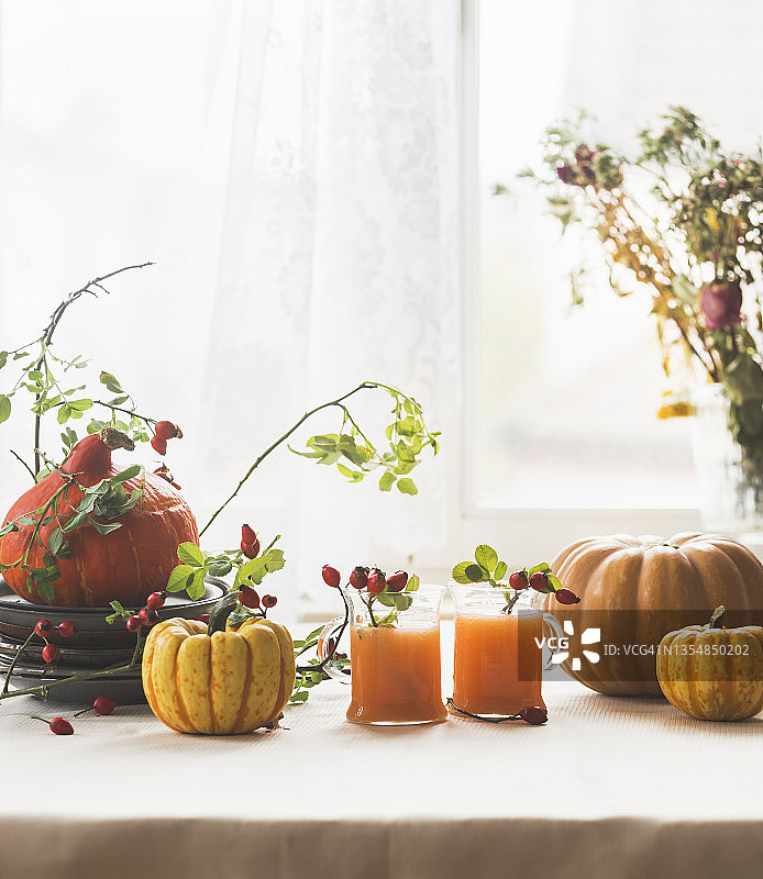 窗边浅色桌子上的南瓜和两杯玻璃杯南瓜潘趣酒图片素材