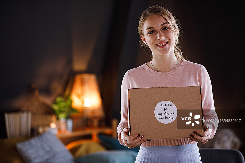 手拿“谢谢”标签包裹并对着镜头微笑的少女图片素材