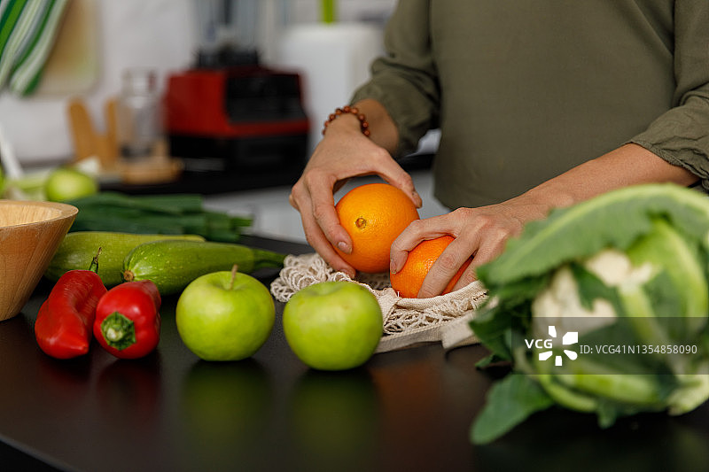 从可重复使用的网袋中取出橙子和其他水果蔬菜图片素材