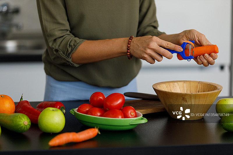 匿名女子削胡萝卜准备午餐图片素材