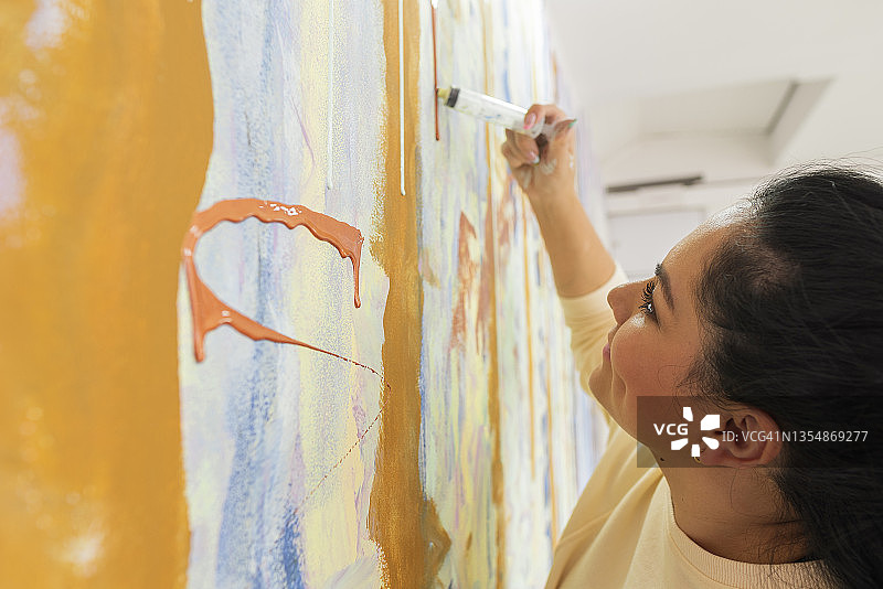 混合油漆颜色时非常开心的拉丁裔女子图片素材