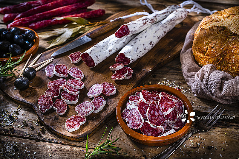 西班牙香肠、橄榄和面包，置于乡村风餐桌上图片素材