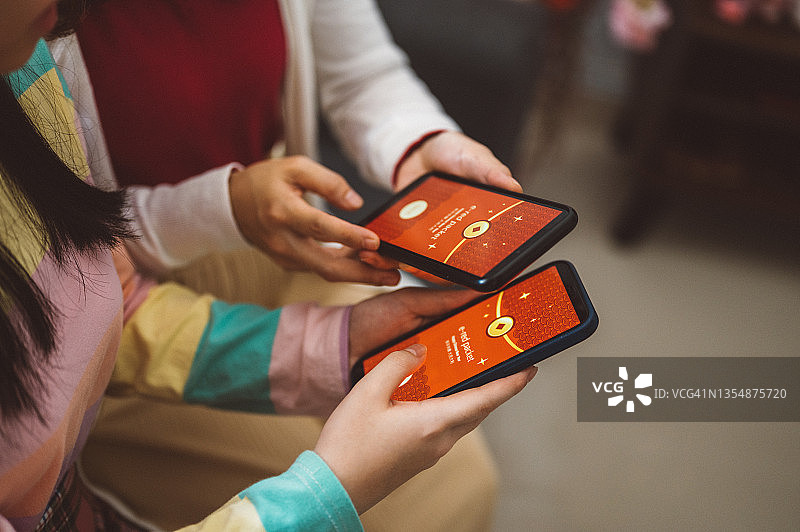 一个亚洲家庭展示数字红包或电子红包，正在智能手机上发送图片素材