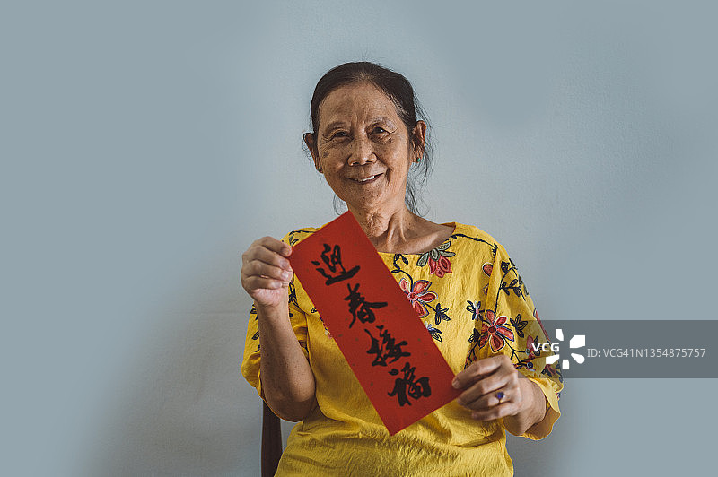 手持中国新年对联的年长亚洲妇女，纯色背景图片素材