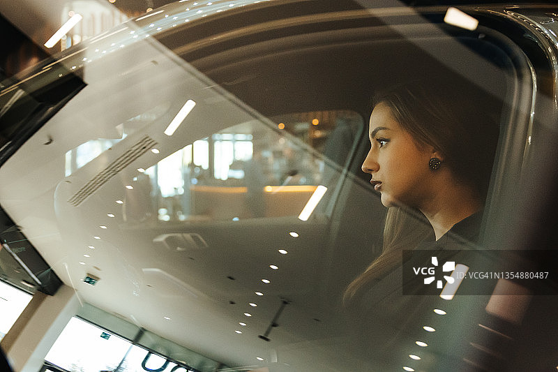 坐在豪华轿车里的现代自信年轻女性的侧视图片素材