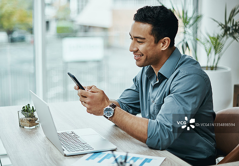 年轻商人在现代办公室使用智能手机和笔记本电脑图片素材
