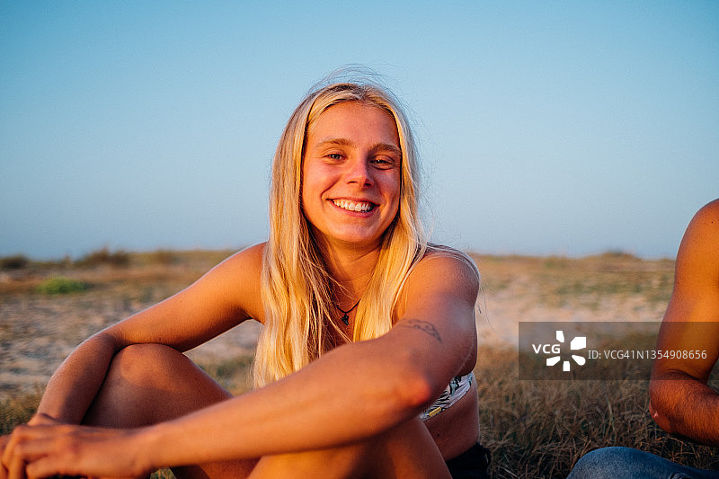 年轻女人坐在沙丘上微笑的肖像图片素材