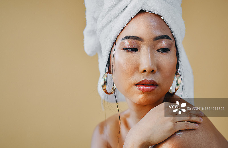 年轻女子在工作室摆姿势，头发裹着毛巾图片素材
