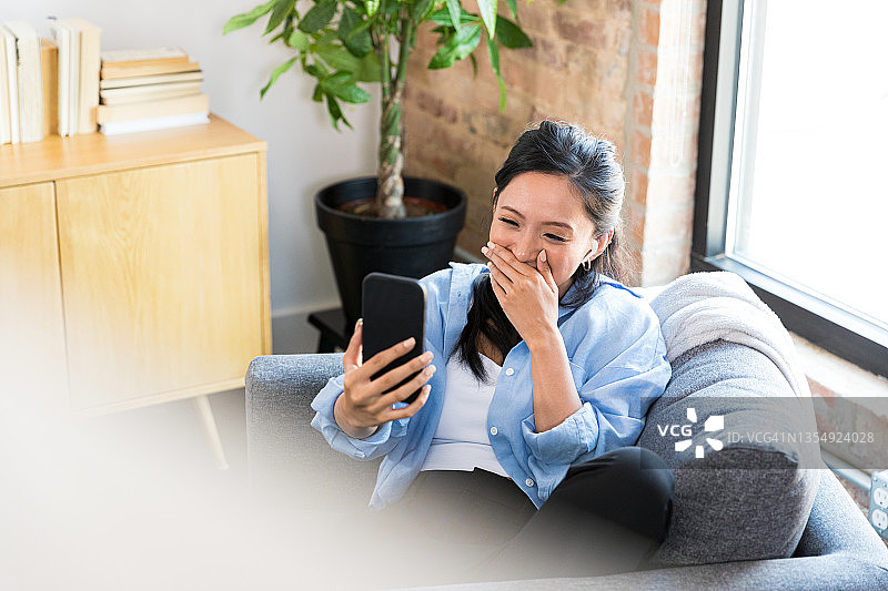 女人看手机捂嘴笑图片素材