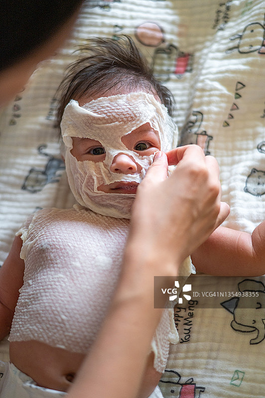 母亲给新生男婴敷自制草药面膜，以治疗皮疹图片素材