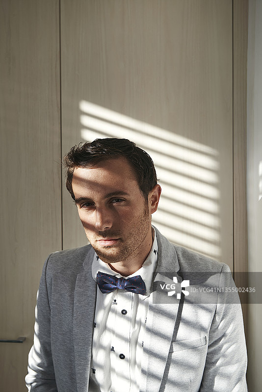 年轻男人穿着西装和领结，表情严肃地看着镜头的肖像图片素材