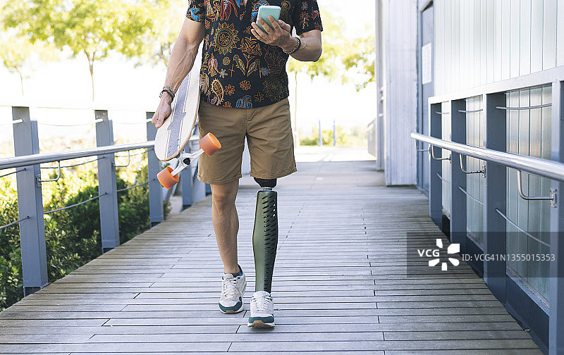 在木板路上使用手机的假肢男人图片素材
