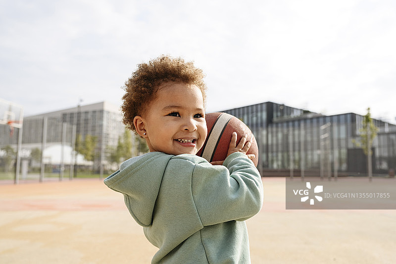 在运动场拿着篮球的可爱女孩图片素材