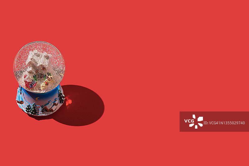 红色背景上的圣诞雪水晶球：圣诞老人、房屋、驯鹿图片素材