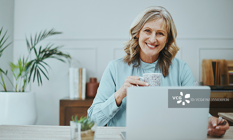 成熟女商人使用笔记本电脑并在现代办公室喝咖啡图片素材