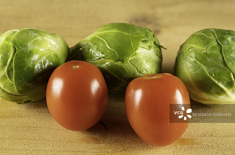 木头上的两颗圣女果和三颗卷心菜图片素材