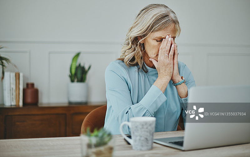 一位成熟的女商人看上去压力很大，在现代化的办公室里工作图片素材