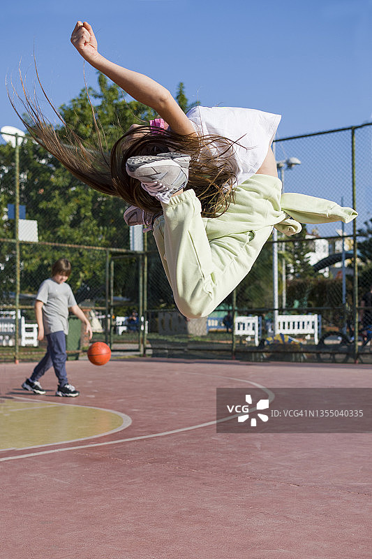 小女孩跳跃，小男孩在篮球场打篮球图片素材
