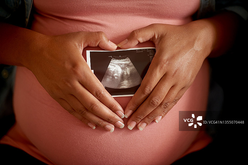 孕妇在家中沙发上手拿胎儿扫描照片的局部照片图片素材