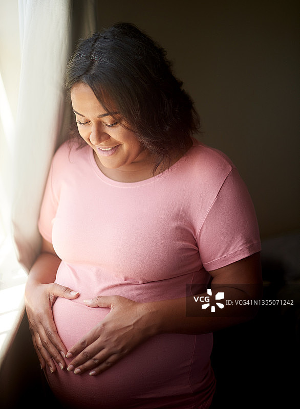 年轻孕妇站在卧室窗边的局部照片图片素材