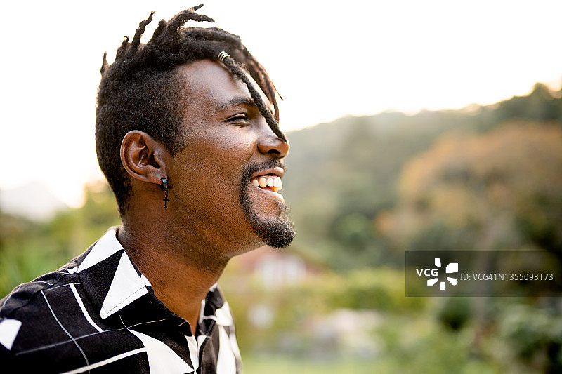 夏天站在外面的有脏辫的开怀大笑的年轻男人图片素材