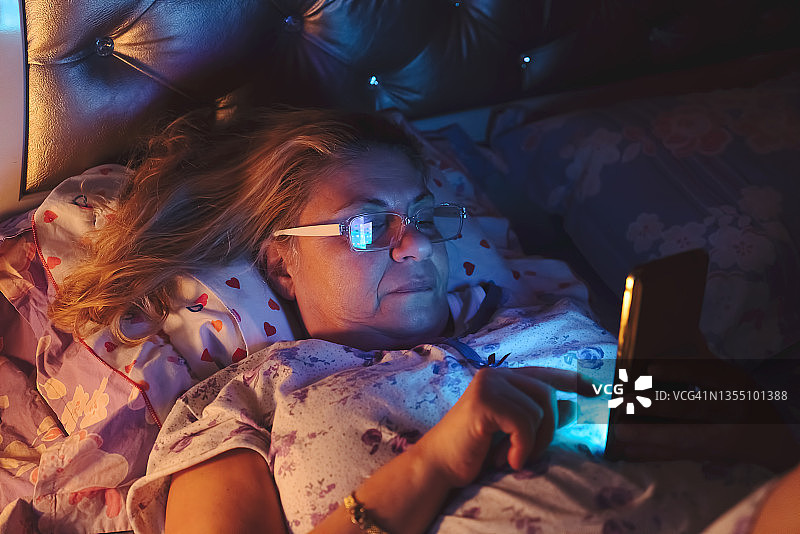 在床上使用手机的老年妇女图片素材