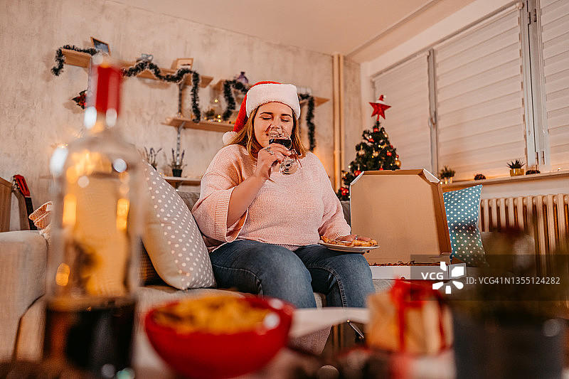 女子在圣诞节享用披萨和葡萄酒图片素材