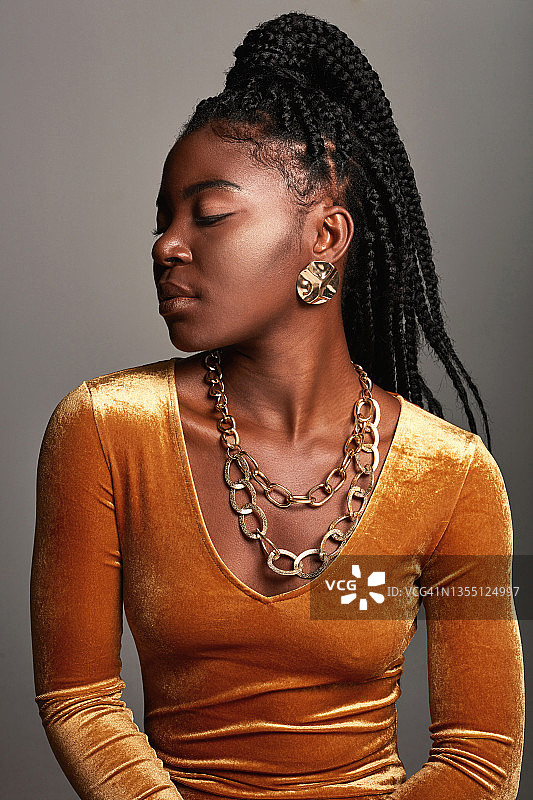 一个美丽的年轻女子在灰色背景下摆姿势图片素材