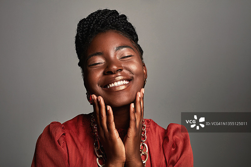 一个美丽的年轻女子在灰色背景下摆姿势图片素材